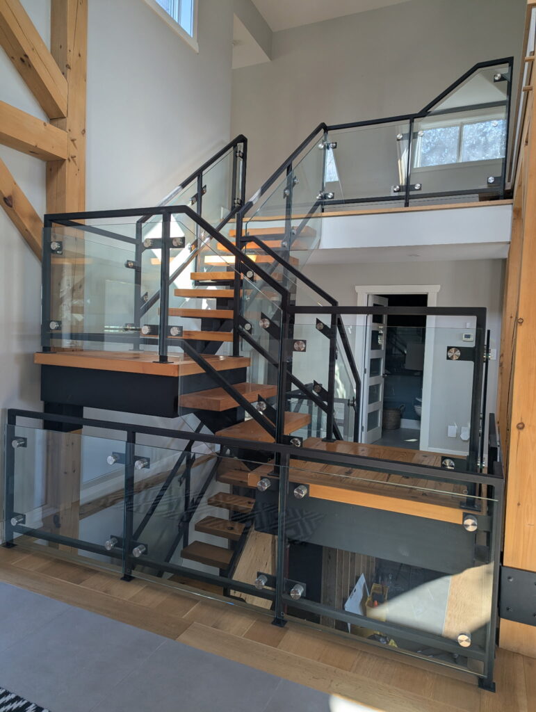 Elegant interior glass railing with black metal frames and posts, installed in Ottawa