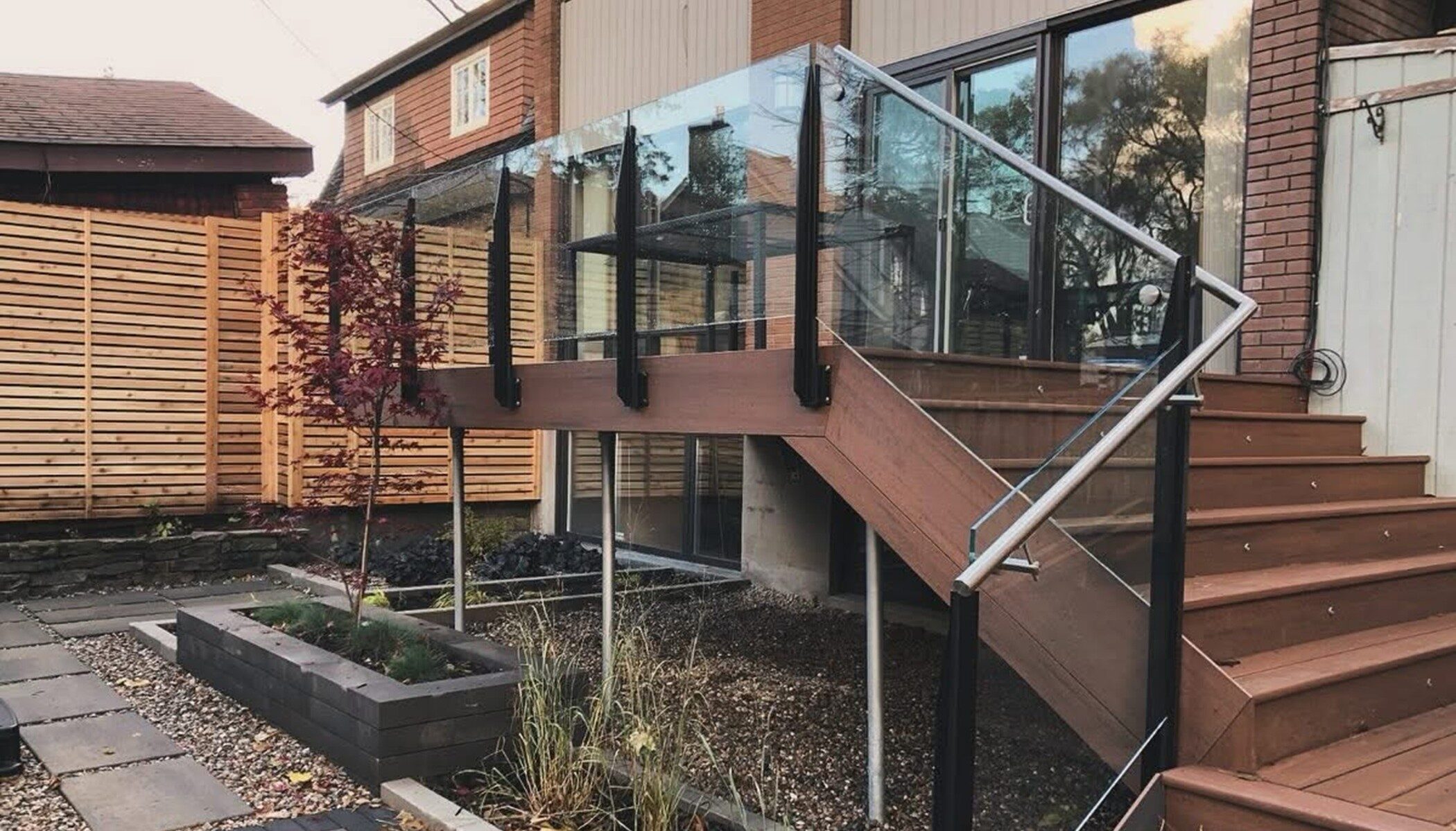 Outdoor Glass Railing on wooden stairs and landing space, fabricated and installed by Raw Glass